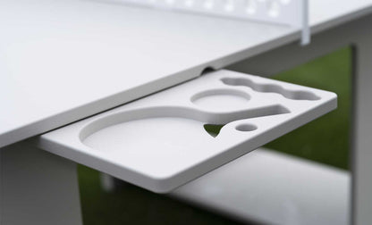 White pull-out side tray with molded drink and accessory holders beneath an outdoor ping pong table.