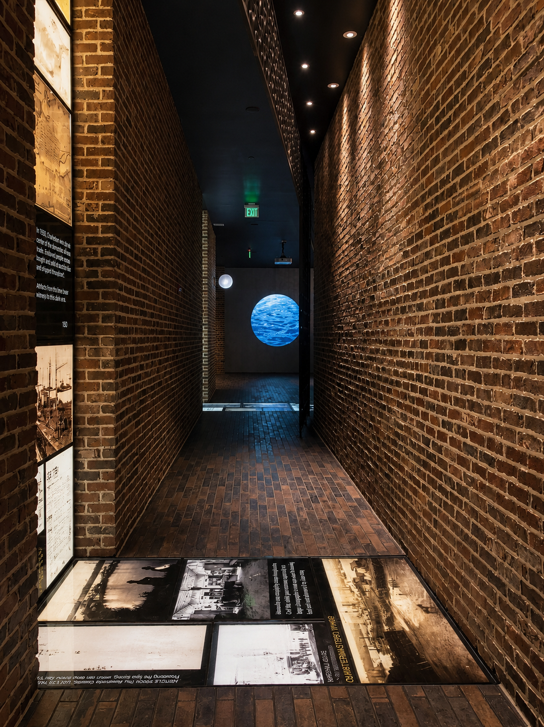 Brick-walled hallway with informational displays and a glowing blue sphere at the end.