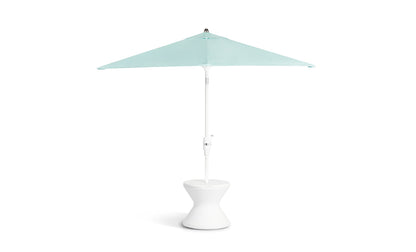 White pedestal-style side table with a tapered hourglass shape holding an umbrella.