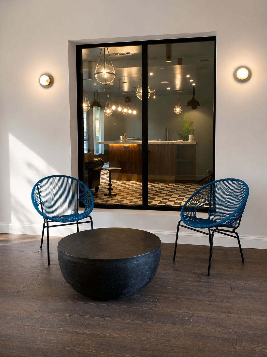 Modern exterior with blue chairs and a round black table in front of a glass door.