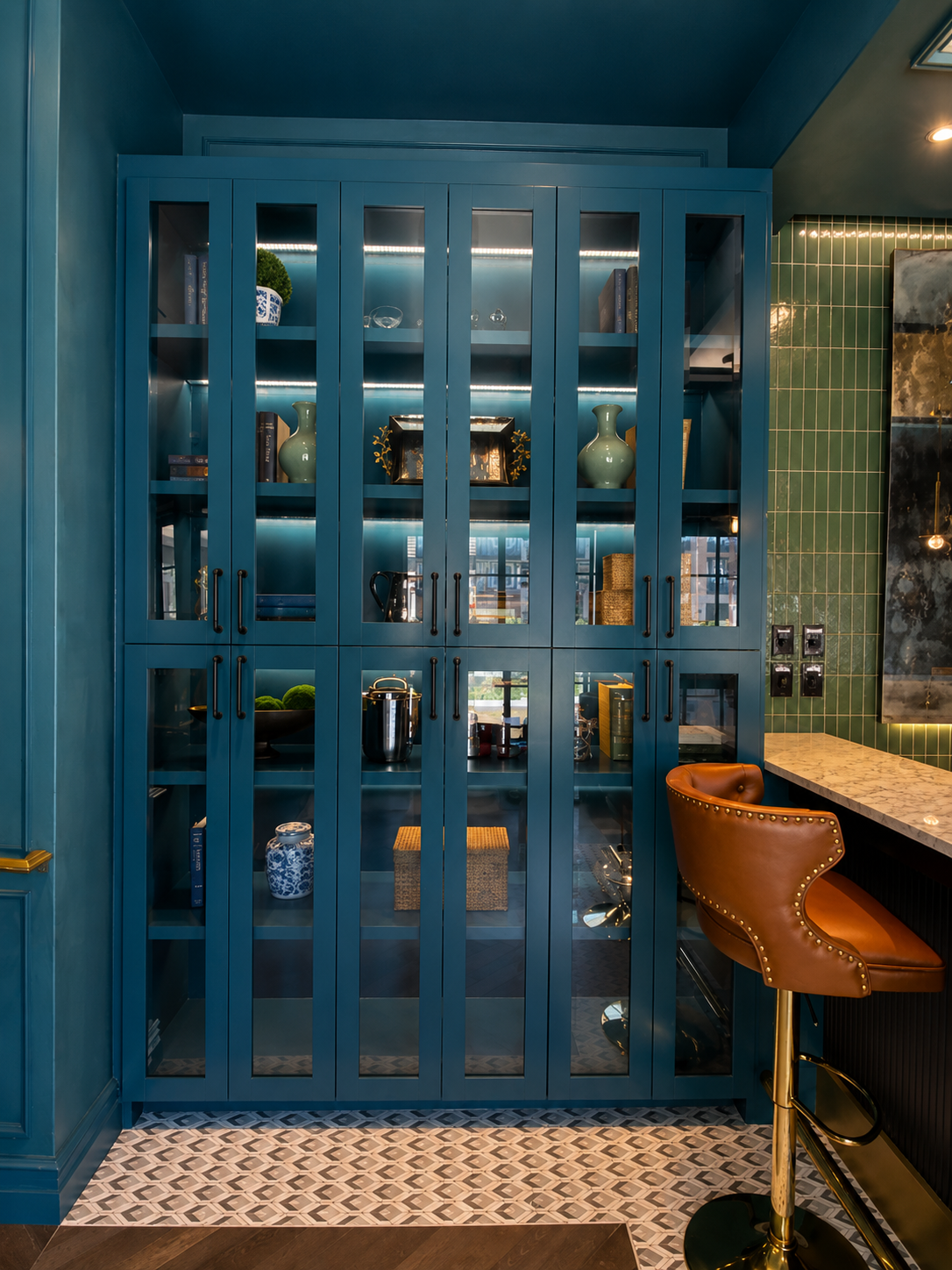 Blue glass-fronted cabinet with decorative items in a room with a bar area.