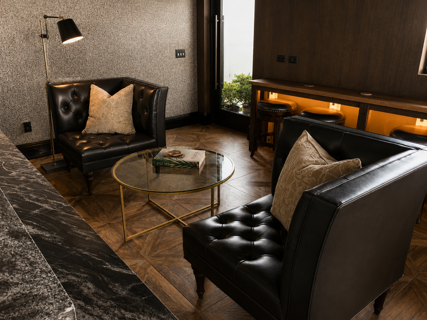 Modern lounge room with black leather sofas, a glass coffee table, and decorative pillows.