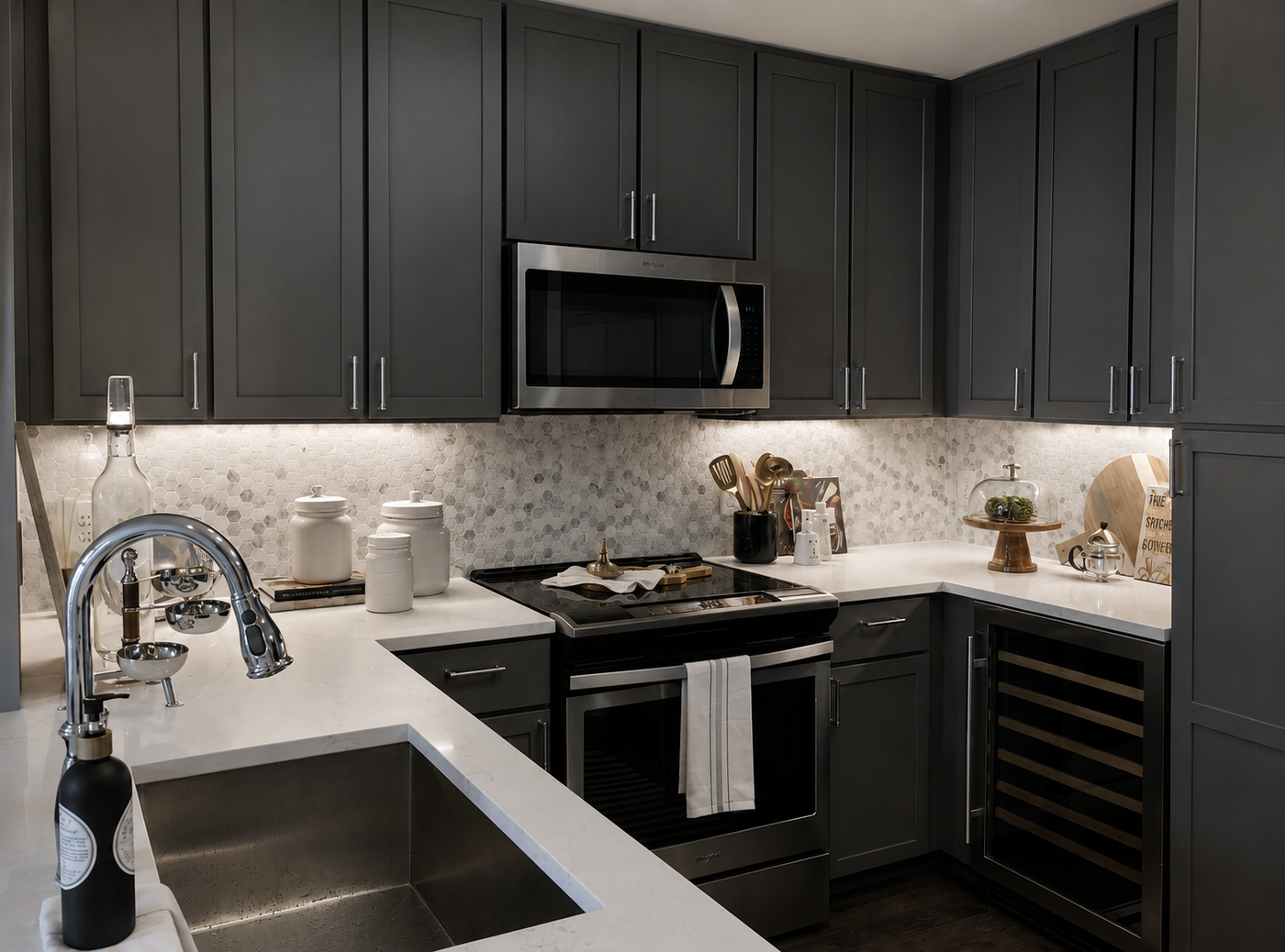 Modern kitchen with dark cabinets, stainless steel appliances, and white countertops.