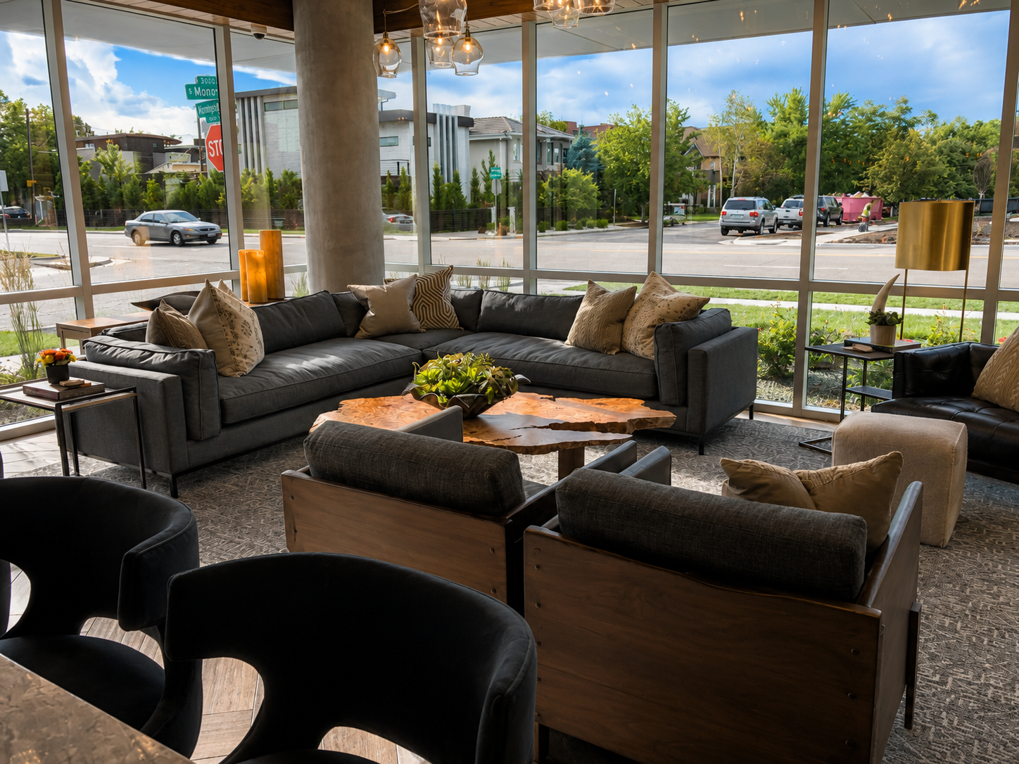 Modern two story waiting area with gray sofa, armchairs, and a coffee table in a well-lit area.