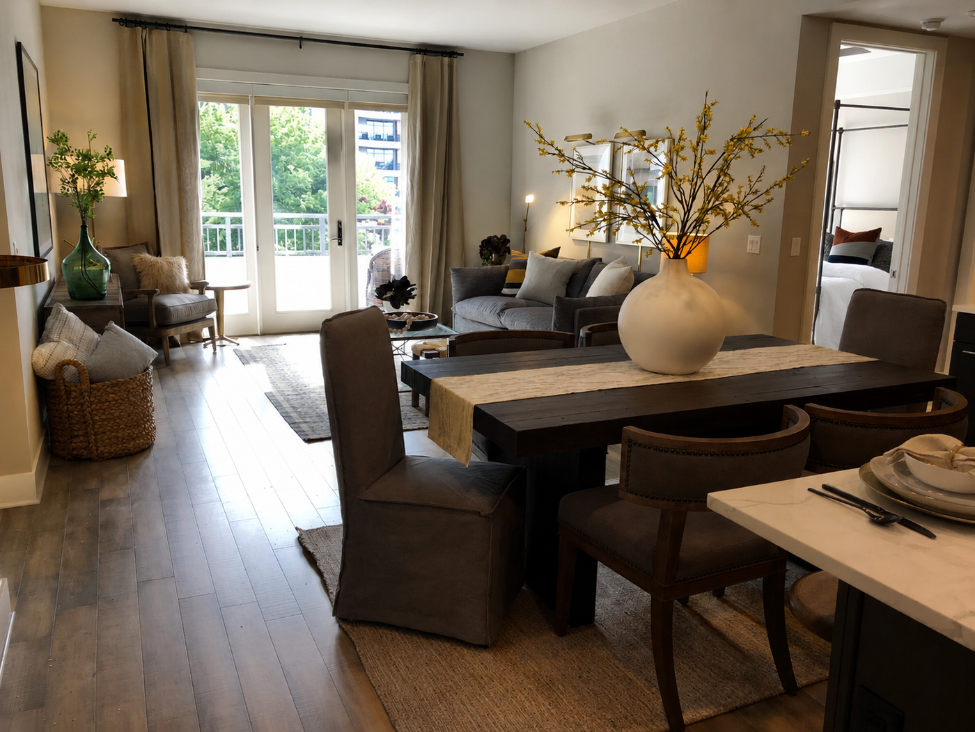 Modern living room with a dining table and chairs, large windows, and decorative elements.