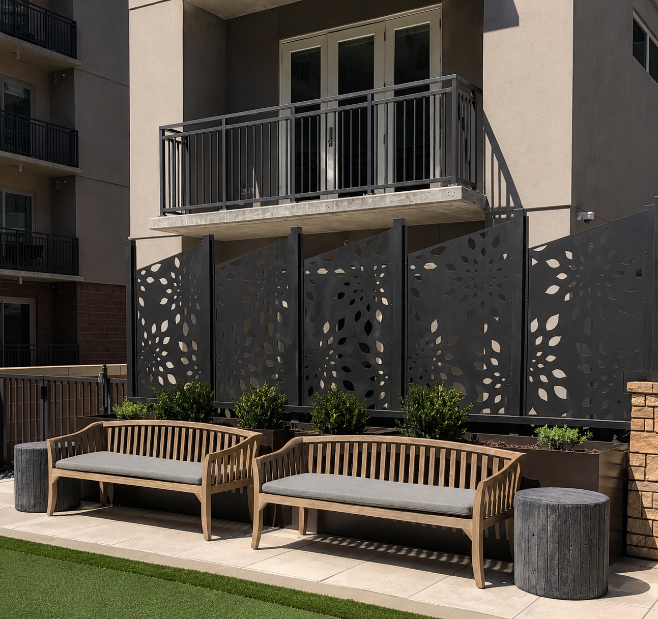 Two wooden benches with gray cushions in front of a building with decorative screen panels.
