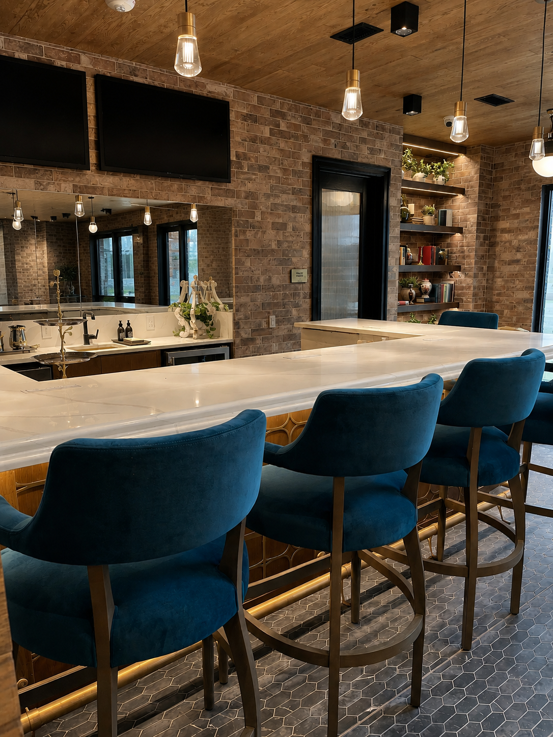 Modern kitchen with a bar area featuring blue chairs and a brick wall.
