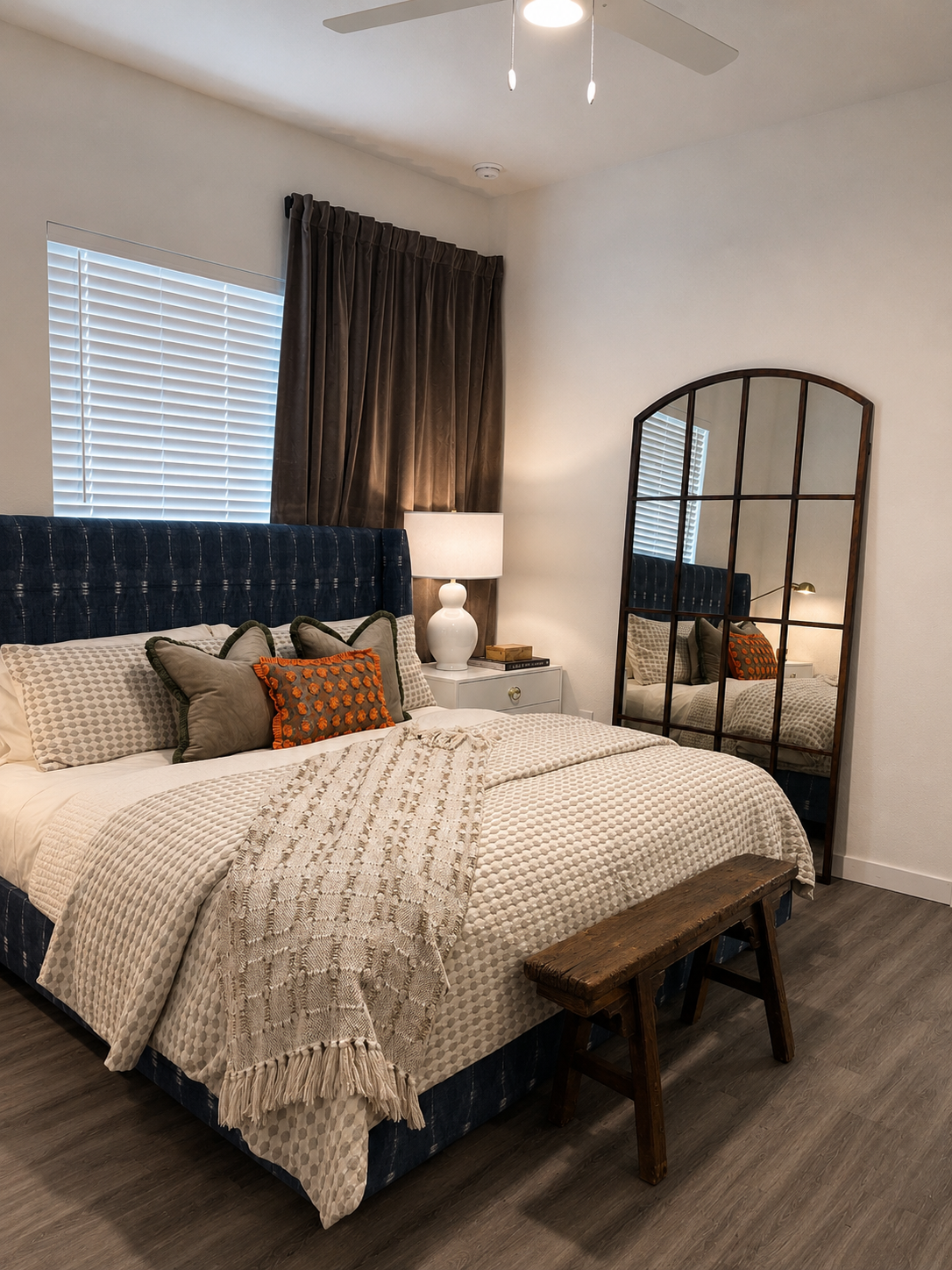 Neatly arranged bedroom with a bed, mirror, and decor elements.