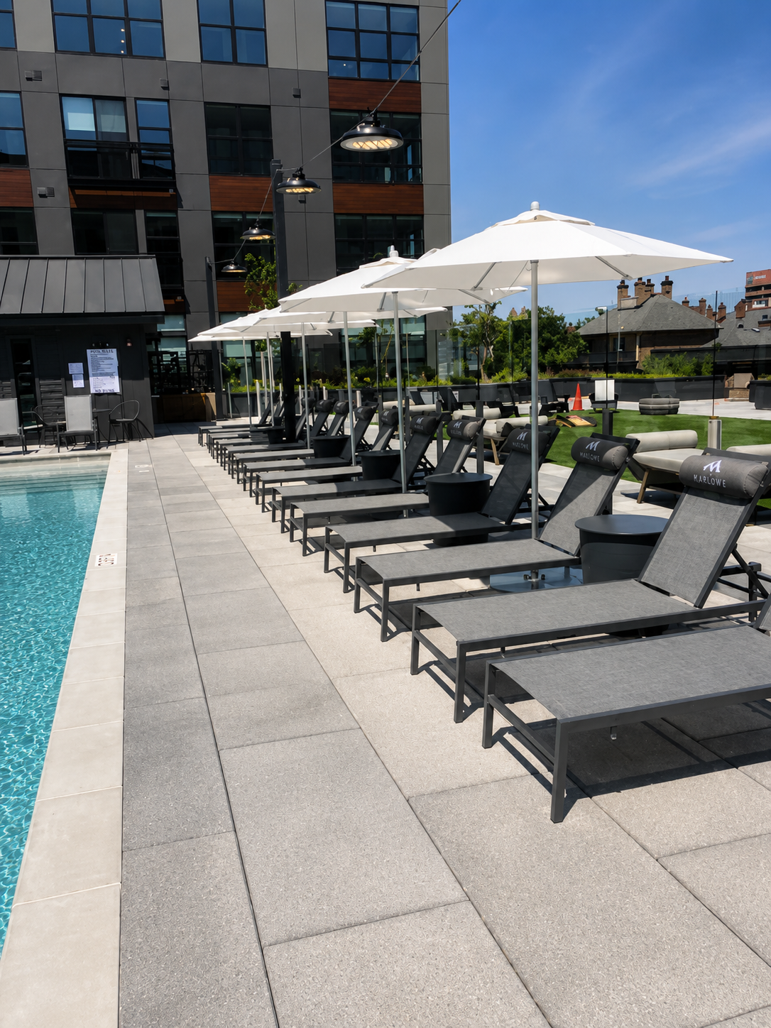 Row of lounge chairs and umbrellas by a poolside with a building in the background