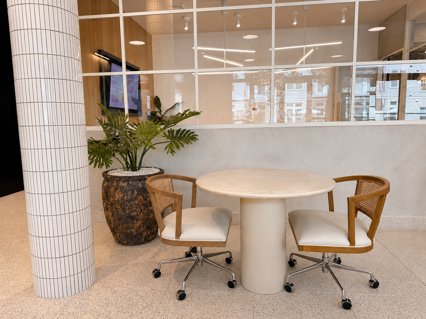Modern waiting area setup with a round table and chairs near a large window.