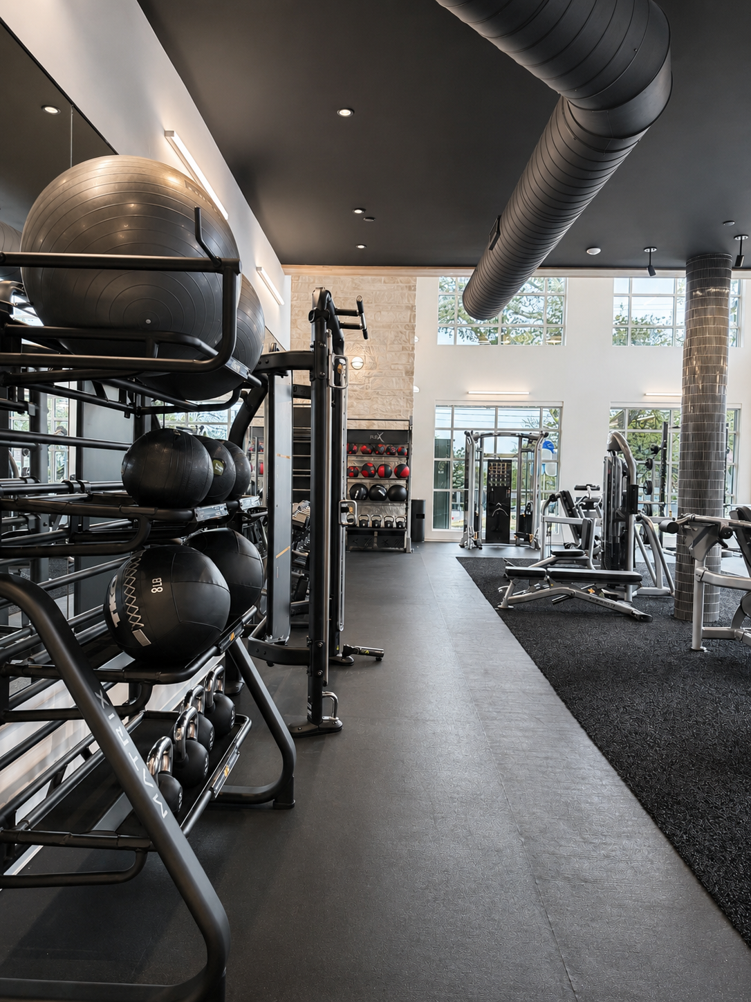 Modern gym interior with exercise equipment and large windows.