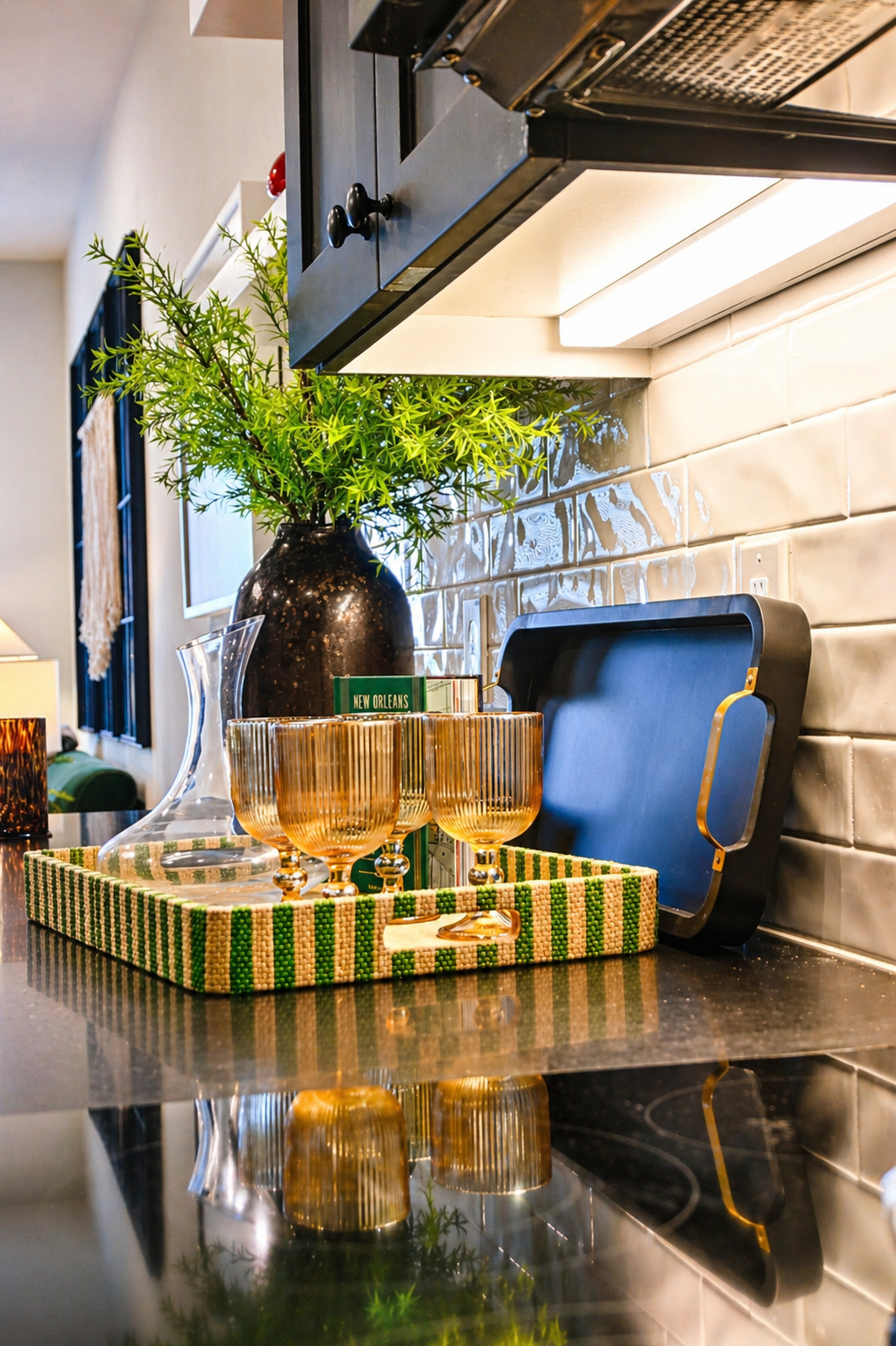 Decorative setting with glasses, a decanter, and a tray on a kitchen counter.