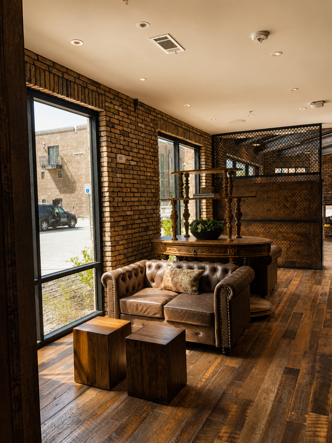 Cozy interior with a brown leather sofa, wooden tables, and brick walls.